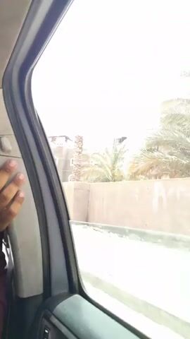 The video, shot from the inside of a moving vehicle, shows a view of buildings along a street.  The buildings are mostly low-rise and appear to be residential. Some have fences or walls around them. The street seems to be unpaved, with patches of dirt and debris.  Power lines are visible overhead. The overall impression is of a somewhat undeveloped or neglected urban area.  The sky is overcast. Music is playing in the background.