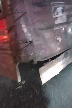 Damaged red vehicle documented in Dhaka with torn metal