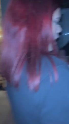 A woman with red hair turns and points to an area, and then the camera pans to another woman with brown hair singing into a microphone. The setting seems to be a house, possibly a karaoke party.
