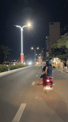 Two-passenger scooter travels waterfront road in Nha Trang