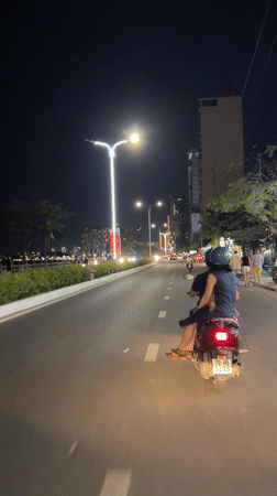 Two-passenger scooter travels waterfront road in Nha Trang