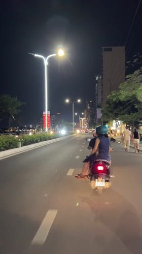Two-passenger scooter travels waterfront road in Nha Trang