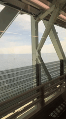 Train crosses bridge near Izumisano with ocean views captured