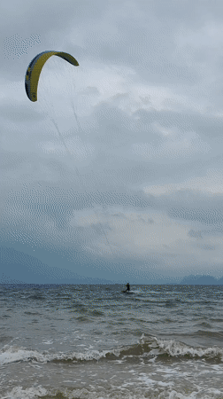Kitesurfers ride choppy waves under cloudy skies in Vietnam