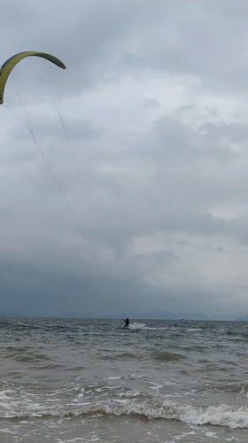Kitesurfers ride choppy waves under cloudy skies in Vietnam