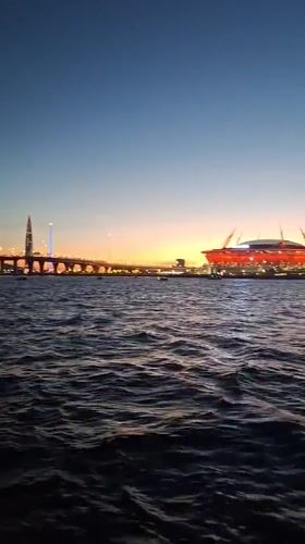 Gazprom Arena glows red over Saint Petersburg's waterfront at dusk
