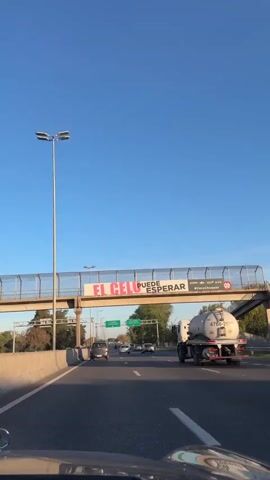 The video shows a driver's perspective on a highway. Overhead signs indicate directions to C. Casares, Buenos Aires and Avellaneda. A tanker truck is in the adjacent lane. Other cars are visible on the highway. The sky is blue and clear. Trees line the side of the road. The video appears to be taken during the day.