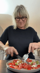 Woman prepares salad, eats bread in French kitchen