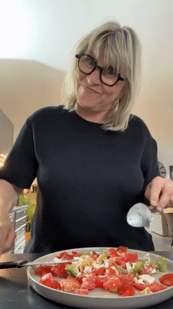 Woman prepares salad, eats bread in French kitchen