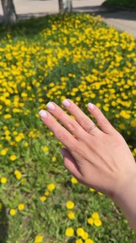 Woman photographed in Russian dandelion field wearing wedding rings