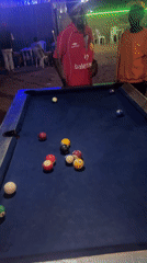 Men play nighttime pool game at Gura Top establishment