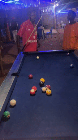 Men play nighttime pool game at Gura Top establishment