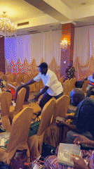 Man throws chairs in decorated hall in Itirin, Nigeria