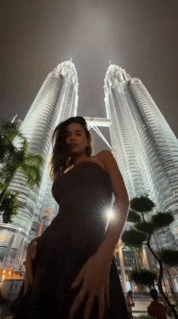 Tourists pose for nighttime photos at Petronas Twin Towers