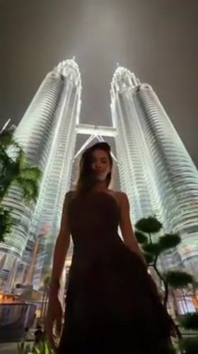 Tourists pose for nighttime photos at Petronas Twin Towers