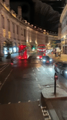 London nighttime street scene with buses, billboards documented