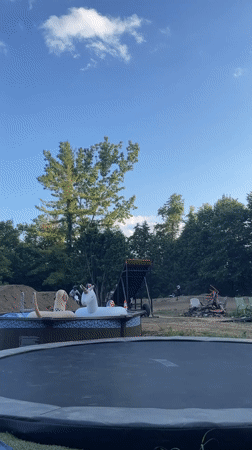 Backyard ramp jumps on a dirt bike, pool and airbag in frame