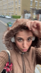 Woman in hooded jacket walks past graffitied London street