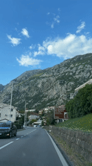 Car travels mountain road near historic church in Montenegro