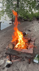 Campfire and paddleboarding at dusk on a Russian riverbank