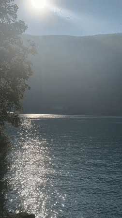 Yellow seaplane takes off from a turquoise Alpine lake