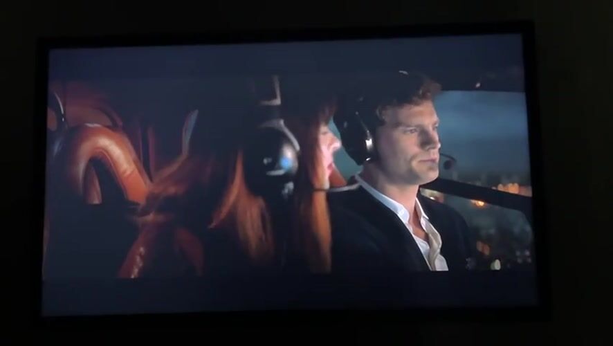 Person watches helicopter scenes, "Fifty Shades" on screen