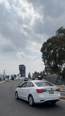White car drives curved Puebla road near hilltop tower