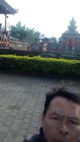 Evening documentation captures Balinese temple, sacred tree, parked vehicle