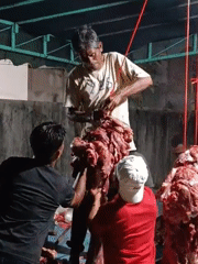 Men prepare meat outdoors in Lhokseumawe, Indonesia