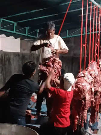 Men prepare meat outdoors in Lhokseumawe, Indonesia