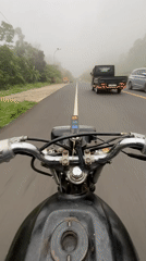 Motorcyclist navigates foggy road conditions in Karangmangu, Indonesia