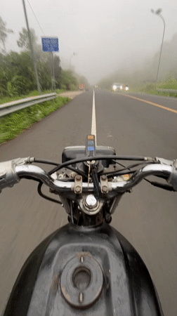 Motorcyclist navigates foggy road conditions in Karangmangu, Indonesia