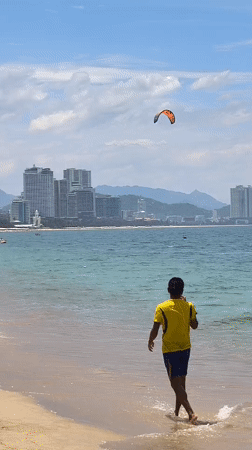 Quiet morning on Nha Trang beach, kiteboarder out on the water
