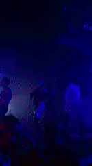 Saxophonist performs at nightclub with dancers and colored lighting