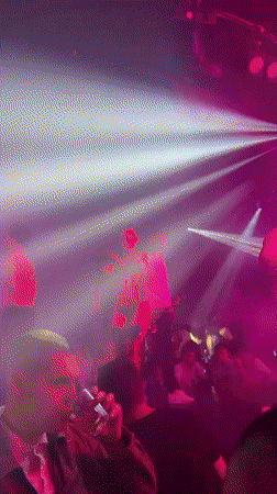 Saxophonist performs at nightclub with dancers and colored lighting