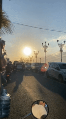 Motorcycle rider documents morning street scenes in Madiun, Indonesia