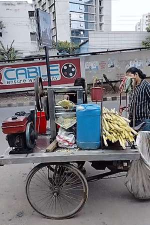Street vendor operates sugarcane juice cart in Dhaka