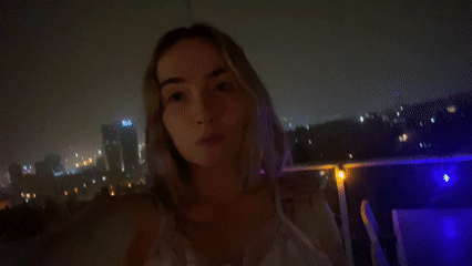 Woman enjoys decorated balcony view of Haifa nightscape