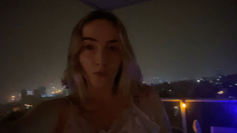 Woman enjoys decorated balcony view of Haifa nightscape