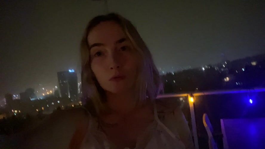 Woman enjoys decorated balcony view of Haifa nightscape