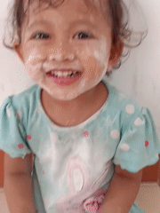 Flour-covered toddler on tiled floor in Badas, Indonesia