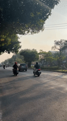 Evening traffic flows through a tree-lined street in Gelam