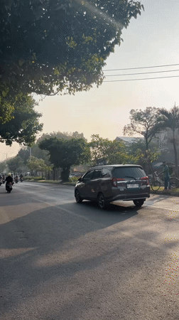 Evening traffic flows through a tree-lined street in Gelam