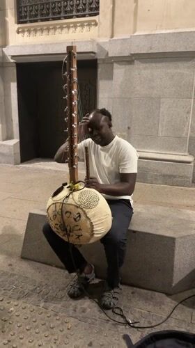 Kora player busking outside an ornate Madrid building