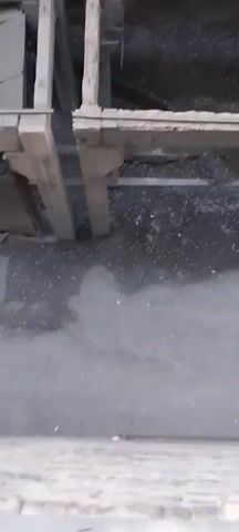 The video shows a panning view of a derelict industrial building. The walls are crumbling, and debris is scattered everywhere. Large pipes and metal structures are visible, suggesting the building was once a factory or processing plant. The overall impression is one of decay and abandonment.