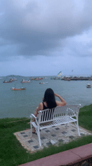 Woman sits on bench overlooking ocean in Weligama, Sri Lanka