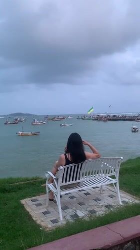 Woman sits on bench overlooking ocean in Weligama, Sri Lanka