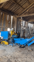 Worker operates log splitter in Russian barn