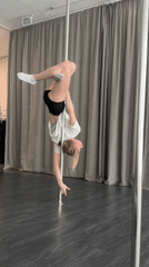 Woman practices pole dance exercises in indoor studio