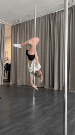 Woman practices pole dance exercises in indoor studio